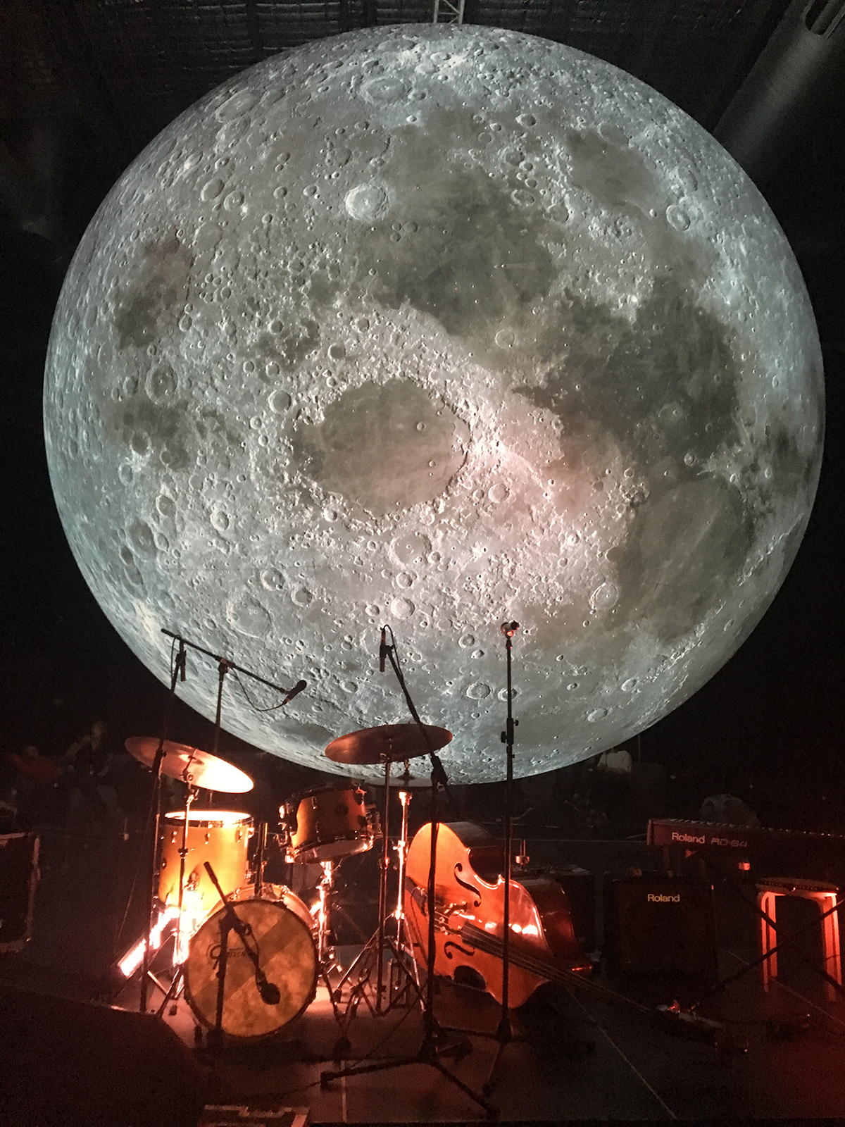 moon sculpture in light with band equipment in red light beneath