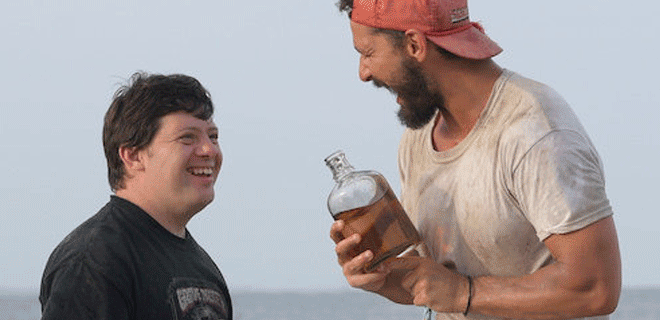 tyler and zack share whiskey on the beach in the peanut butter falcon movie