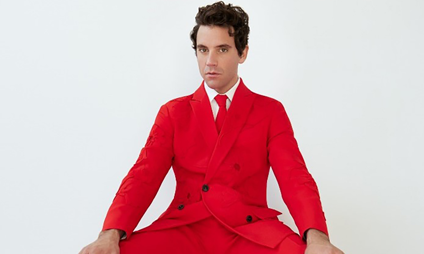 mika grace kelly and other wonderful songs - a picture of mika sitting in a bright red suit