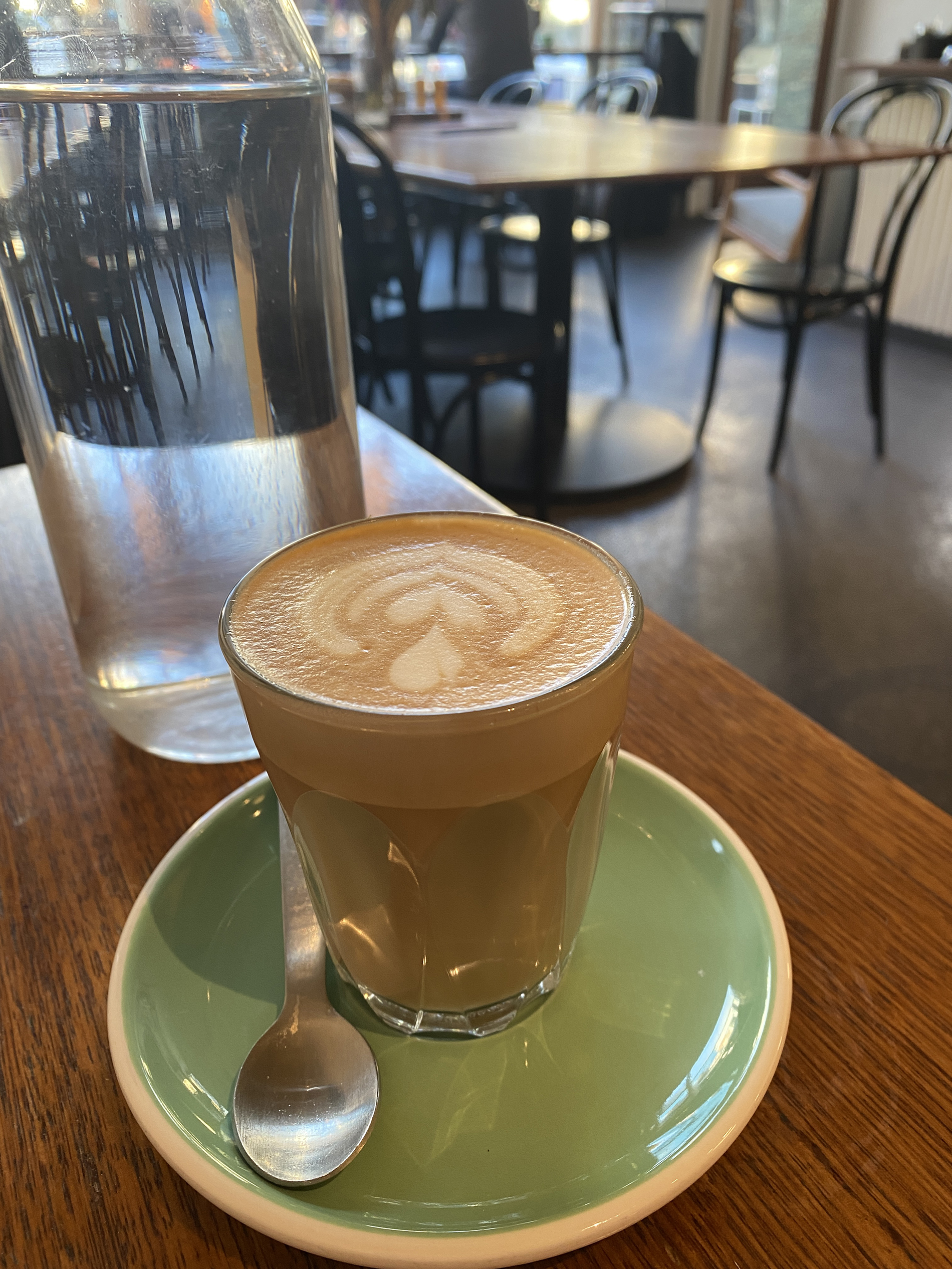 arcadia cafe fitzroy on gertrude street - picture of soy latte in glass with water, tables and chairs behind