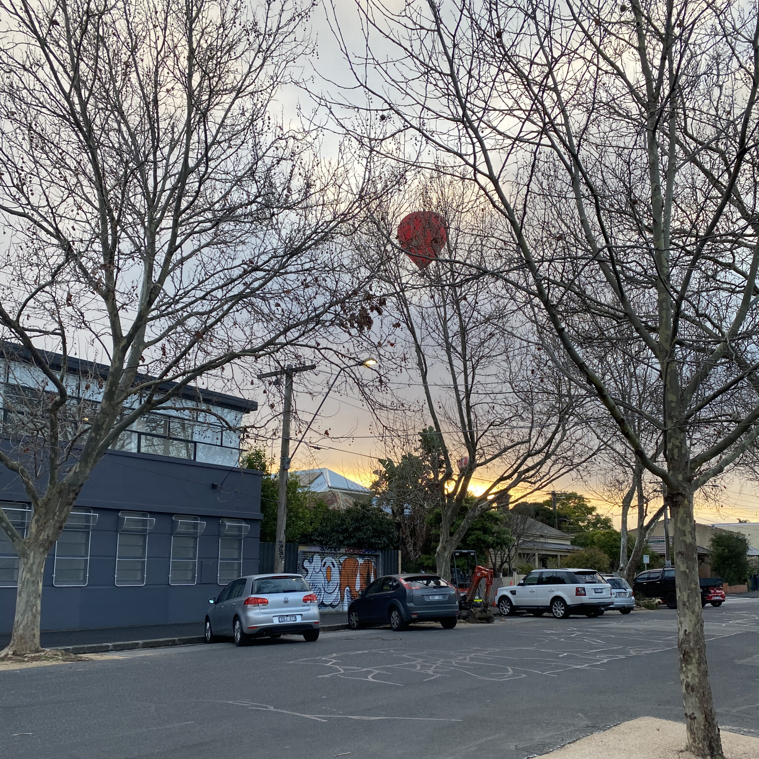 walking around collingwood today - 5th august 2023 - two hot air balloons in the sky - a red one and a red and white striped through the dawn light!